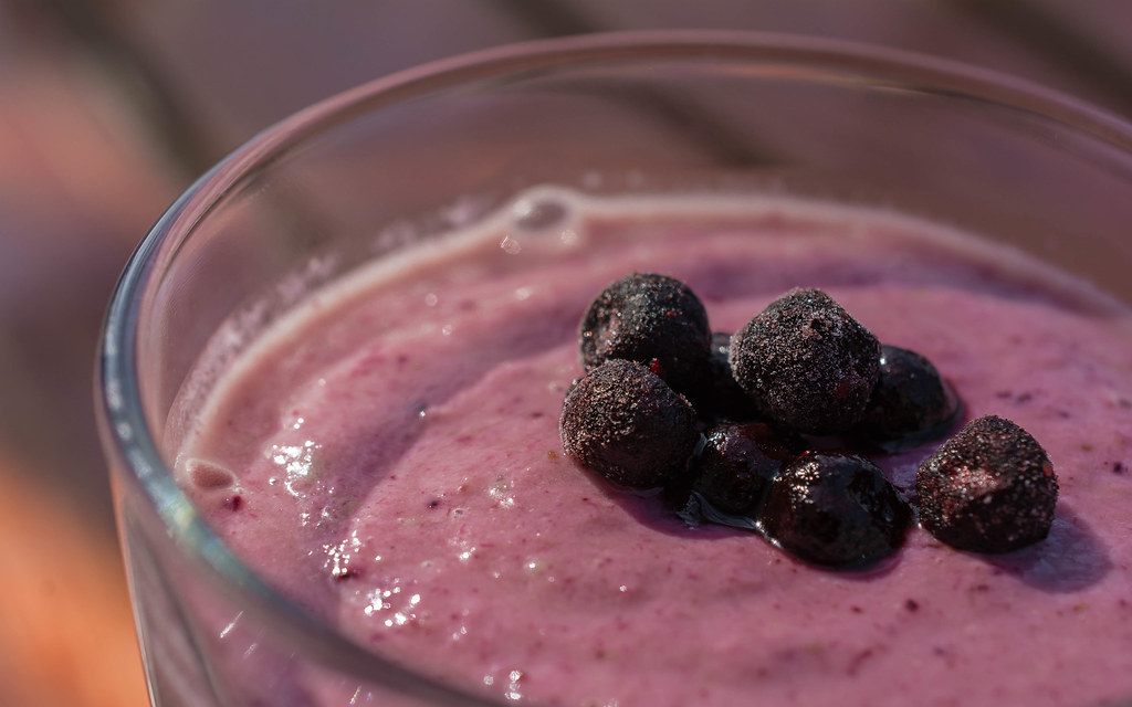 A blueberry smoothie in a glass, berries on top
