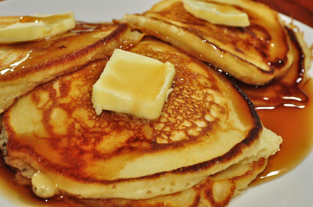 A stack of pancakes with butter and syrup
